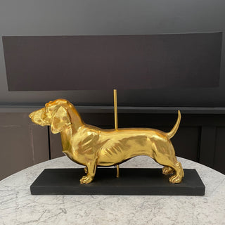 Gold sausage dog table lamp with a black rectangular lamp shade